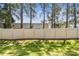 View of backyard with grass, white privacy fence and tall trees in the distance creating a serene outdoor space at 5150 Bay Isle Cir, Clearwater, FL 33760