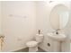 White pedestal sink and toilet in a well-lit, minimalist half bathroom with neutral walls at 6967 Silverado Ranch Blvd, Zephyrhills, FL 33541