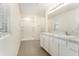 Bright bathroom featuring dual sinks, white cabinets, and a separate tiled shower area at 6967 Silverado Ranch Blvd, Zephyrhills, FL 33541