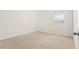 A bright bedroom featuring a window and neutral carpeting provides a blank canvas for personalization at 6967 Silverado Ranch Blvd, Zephyrhills, FL 33541