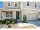 Close up of the front door with tan stucco and a two car garage on a sunny day at 6967 Silverado Ranch Blvd, Zephyrhills, FL 33541