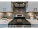 Close up of kitchen stove and backsplash with stainless steel range hood and wall-mounted cabinetry at 712 Estates Blvd, Tarpon Springs, FL 34689
