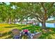 Tranquil backyard with mature shade tree, waterfront view, lush lawn, and outdoor seating area at 732 Kingston Ct, Apollo Beach, FL 33572