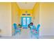 Inviting covered entryway with stylish blue chairs, bright yellow walls, and a decorative nautical accent at 732 Kingston Ct, Apollo Beach, FL 33572