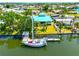 Waterfront home with a private dock, boat, and mature landscaping, featuring a striking blue roof and lush lawn at 732 Kingston Ct, Apollo Beach, FL 33572