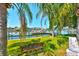 Waterfront view featuring a private boat dock, tranquil waters, lush lawn, and swaying palm trees at 732 Kingston Ct, Apollo Beach, FL 33572