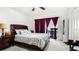 Bedroom featuring a bed, large window with red curtains, ceiling fan, and side table with a lamp at 7321 Central Ave # 503, St Petersburg, FL 33710