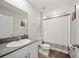 Well-lit bathroom with a modern vanity, toilet, and a shower with a white curtain and dark hardware at 7797 Peace Lily Ave, Wesley Chapel, FL 33545