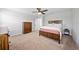 Neutral bedroom features carpeted floors, ceiling fan, and wood frame bed with a white comforter at 7797 Peace Lily Ave, Wesley Chapel, FL 33545