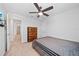 Cozy bedroom featuring neutral tones, a ceiling fan, and an open doorway to a carpeted hallway at 7797 Peace Lily Ave, Wesley Chapel, FL 33545