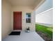 A cozy front porch features a neutral colored door with modern fixtures and potted plants at 7797 Peace Lily Ave, Wesley Chapel, FL 33545