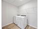 Clean laundry room with a washer and dryer set on a wood-look floor, complemented by white walls at 7797 Peace Lily Ave, Wesley Chapel, FL 33545