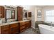 Bathroom features a double sink vanity with granite countertop, custom cabinetry, and a soaking tub at 826 Christina Cir, Oldsmar, FL 34677