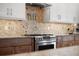 Close-up of the kitchen stove with mosaic backsplash, stainless steel appliances, and granite countertops at 826 Christina Cir, Oldsmar, FL 34677