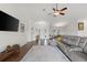Bright living room featuring a large gray leather sofa, modern ceiling fan, and dark wood flooring at 826 Christina Cir, Oldsmar, FL 34677
