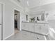 Well-lit main bathroom featuring double sinks, granite counters, a tub, and walk-in closet access at 8607 Bower Bass Cir, Wesley Chapel, FL 33545