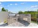 Outdoor kitchen with built-in grill, stainless steel storage, and stone accents at 8607 Bower Bass Cir, Wesley Chapel, FL 33545