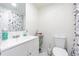 Well-lit bathroom featuring white fixtures, a stylish shower curtain, and ample storage at 9031 Westchester Cir # 128, Tampa, FL 33604