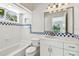 Bright bathroom with a tub, white tiled walls, and a decorative blue tile border at 9265 Treasure Ln Ne, St Petersburg, FL 33702