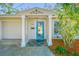 Inviting entryway with a decorative blue door, manicured landscaping, and covered entrance at 9265 Treasure Ln Ne, St Petersburg, FL 33702