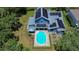 Aerial view of a home with a pool and solar panels on the roof surrounded by lush greenery, perfect for energy efficiency at 9303 Alice Ln, Riverview, FL 33578