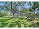 Scenic backyard view with a mature shade tree and playground equipment, perfect for outdoor Gathering activities by the water at 9303 Alice Ln, Riverview, FL 33578