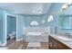Relaxing bathroom featuring a large soaking tub with tiled surround and wood flooring at 9303 Alice Ln, Riverview, FL 33578