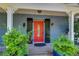 Inviting front entry with a red glass door, decorative black shutters, and manicured potted plants on a covered porch at 9303 Alice Ln, Riverview, FL 33578