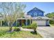 Charming blue two-story home featuring a welcoming front porch, well-manicured landscaping, and a two car garage at 9303 Alice Ln, Riverview, FL 33578