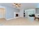 Open-concept living room with white brick fireplace, ceiling fan and neutral tile floors, ideal for relaxation and entertaining at 9303 Alice Ln, Riverview, FL 33578