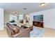 Spacious living room featuring a large TV, leather couch, and a seamless flow into the dining area at 9303 Alice Ln, Riverview, FL 33578