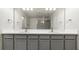 Bathroom showcasing double sink vanity, gray cabinets, large mirror, and walk-in shower at 10127 Newel Valley Loop, Riverview, FL 33569