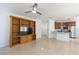 Open-concept living room with tile floors, ceiling fan, and built-in wooden shelving and TV at 10502 Villa View Cir, Tampa, FL 33647