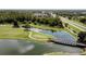 Aerial view of a golf course community with a bridge over a lake and lush trees at 10517 Palm Cove Ave, Tampa, FL 33647