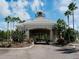 Elegant stone-clad community entrance with lush landscaping and palm trees beneath a bright, partly cloudy sky at 10517 Palm Cove Ave, Tampa, FL 33647