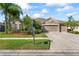 Charming single-story home with a three-car garage, a manicured lawn, and mature landscaping under a blue sky at 10517 Palm Cove Ave, Tampa, FL 33647