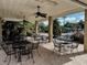 Outdoor patio seating area with tables, chairs, ceiling fans, and view of community pool surrounded by lush tropical landscaping at 10517 Palm Cove Ave, Tampa, FL 33647