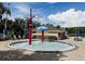 Community splash pad with water features and seating surrounded by lush tropical landscaping and blue umbrellas for shade at 10517 Palm Cove Ave, Tampa, FL 33647