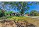 Landscaped front yard with mature trees shading a single-Gathering home and a long driveway at 12923 Colony Rd, Hudson, FL 34669
