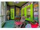 Screened in patio area exhibiting green doors, tiki decor, and quaint outdoor seating at 12923 Colony Rd, Hudson, FL 34669