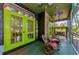 Enclosed patio featuring colorful decor, a swing, a wooden rocking chair and vibrant green doors and flooring at 12923 Colony Rd, Hudson, FL 34669
