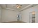 Bright main bedroom with ceiling fan, tray ceiling, and en-suite bathroom entrance at 13637 Blythewood Dr, Spring Hill, FL 34609