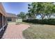 Landscaped backyard showcasing a brick patio, a fire pit, and mature trees at 1416 Buckner Rd, Valrico, FL 33596
