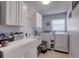 Well-organized laundry room with white cabinets, sink, modern washer and dryer, and tile flooring at 1416 Buckner Rd, Valrico, FL 33596
