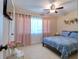Inviting bedroom with a cozy bed, ceiling fan, and pink curtains at 16605 Round Oak Dr, Tampa, FL 33618