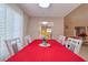 Well-lit dining room with red table cover, seating for six, and view into the kitchen at 16605 Round Oak Dr, Tampa, FL 33618