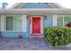 A cozy home entrance showcasing a vibrant red front door, complementing white shutters, and lush greenery at 16605 Round Oak Dr, Tampa, FL 33618