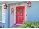 A charming red front door adorned with a wreath, framed by lush greenery and classic white shutters at 16605 Round Oak Dr, Tampa, FL 33618