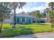Landscaped front yard with mature trees, a lush lawn, and a well-maintained blue home with white trim at 16605 Round Oak Dr, Tampa, FL 33618