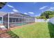 Enclosed pool area with screened enclosure, a brick trim, and a spacious green lawn, ideal for recreation and relaxation at 16605 Round Oak Dr, Tampa, FL 33618